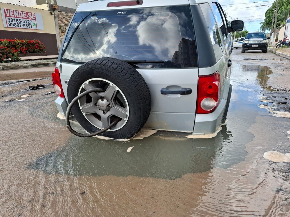 Carro cai em cratera causada por vazamento de tubulação